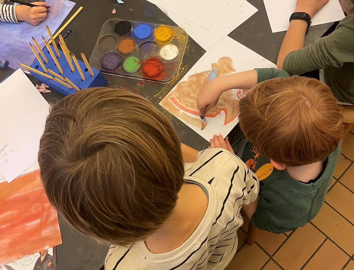 Børn set oppefra, der maler med pastelfarver